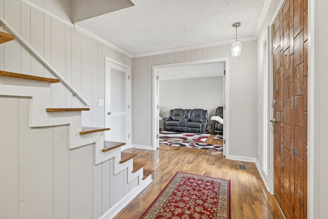 entryway with crown molding, hardwood / wood-style floors, a textured ceiling, and wooden walls