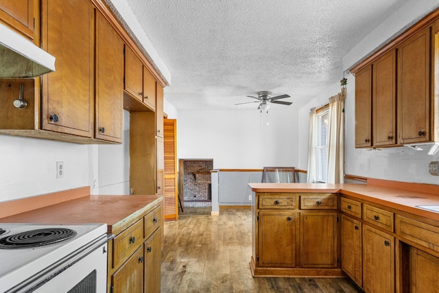 kitchen with ceiling fan, white electric stove, kitchen peninsula, a textured ceiling, and hardwood / wood-style flooring