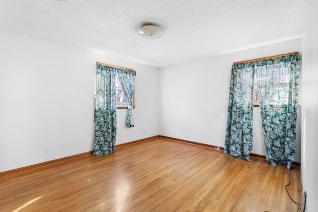 empty room with wood-type flooring, a textured ceiling, and plenty of natural light