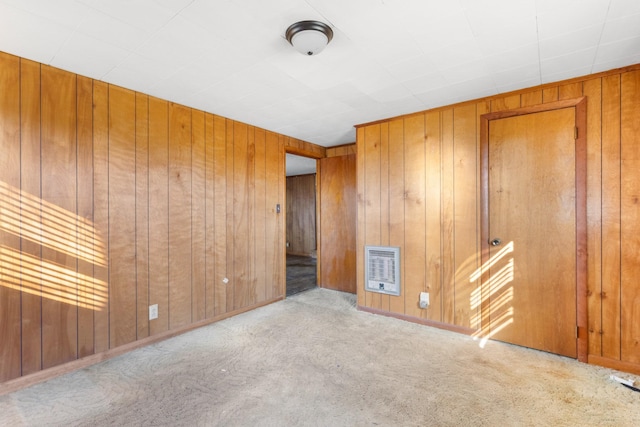 carpeted spare room with heating unit and wood walls