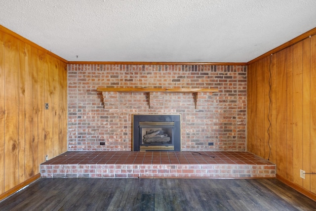 unfurnished living room with wood walls, dark hardwood / wood-style flooring, crown molding, and a textured ceiling