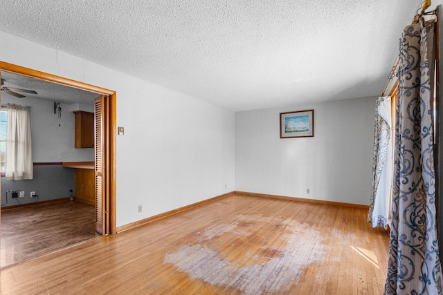 unfurnished room featuring ceiling fan, wood-type flooring, and a textured ceiling