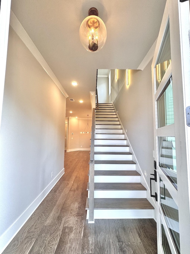 staircase featuring crown molding and hardwood / wood-style flooring