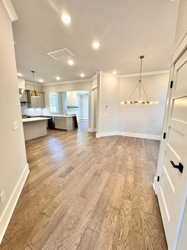 kitchen featuring hanging light fixtures, crown molding, backsplash, and wood-type flooring