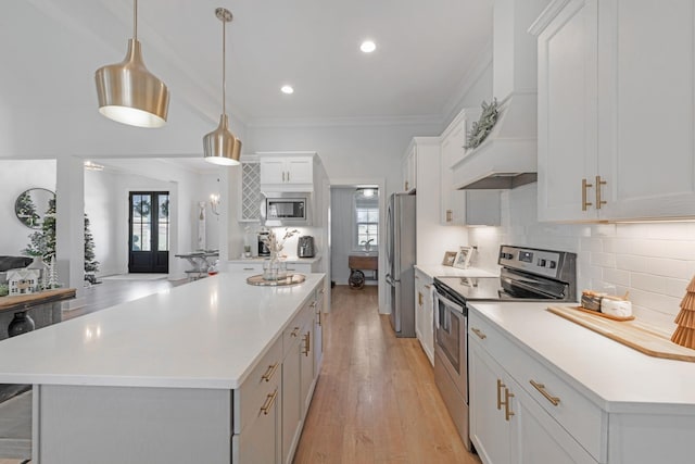 kitchen featuring pendant lighting, crown molding, light wood-type flooring, white cabinetry, and stainless steel appliances