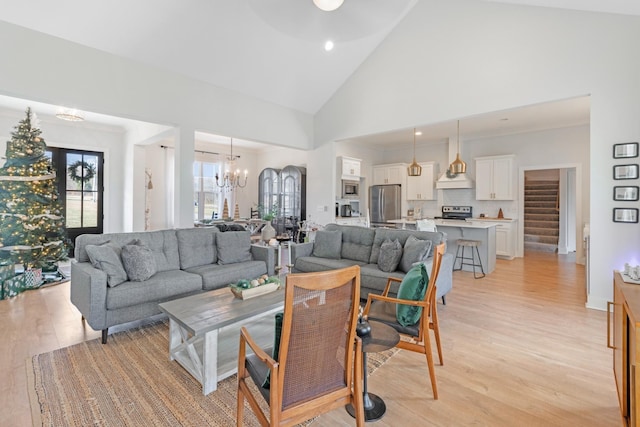 living room featuring a chandelier, light hardwood / wood-style floors, and high vaulted ceiling