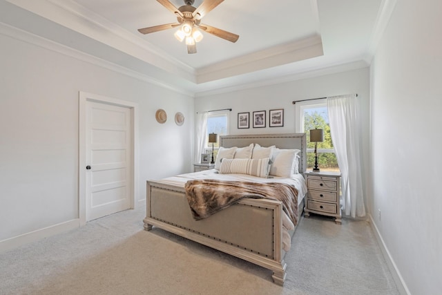 bedroom with a tray ceiling, ceiling fan, crown molding, and light colored carpet