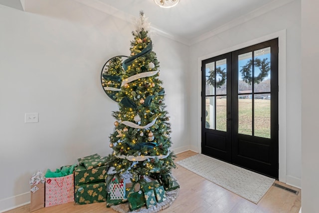 entrance foyer with french doors, hardwood / wood-style flooring, and crown molding