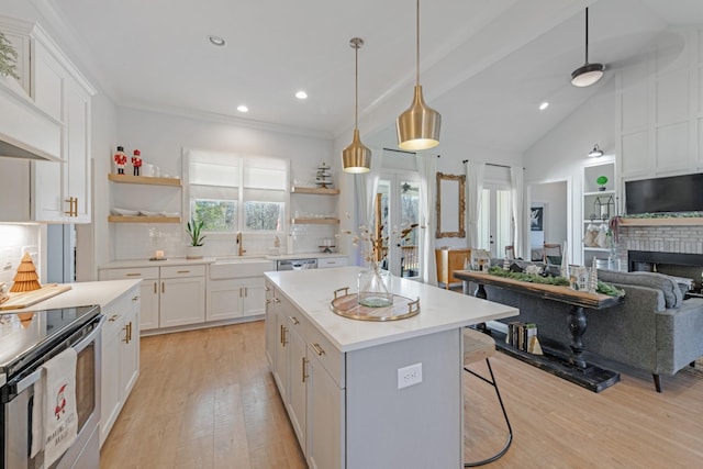 kitchen featuring white cabinetry, a center island, a brick fireplace, decorative light fixtures, and light wood-type flooring