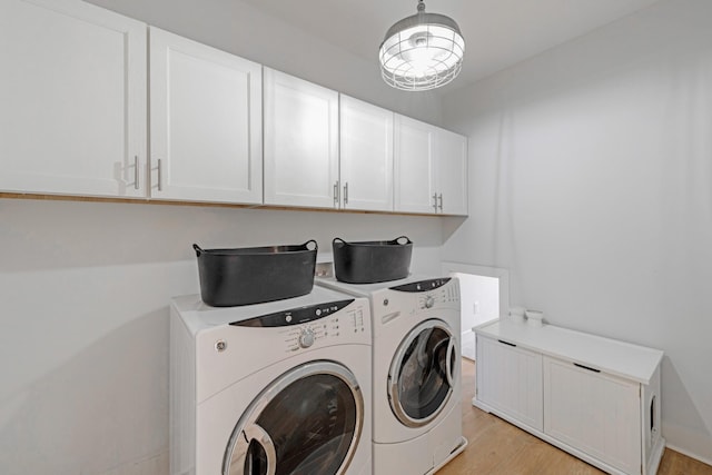 laundry room with washing machine and clothes dryer, cabinets, and light hardwood / wood-style floors