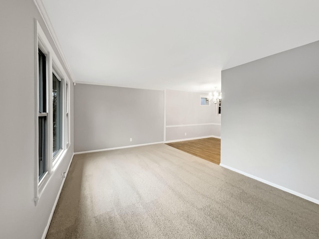 unfurnished room with carpet, an inviting chandelier, and ornamental molding