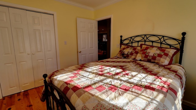 bedroom with hardwood / wood-style floors, crown molding, and a closet