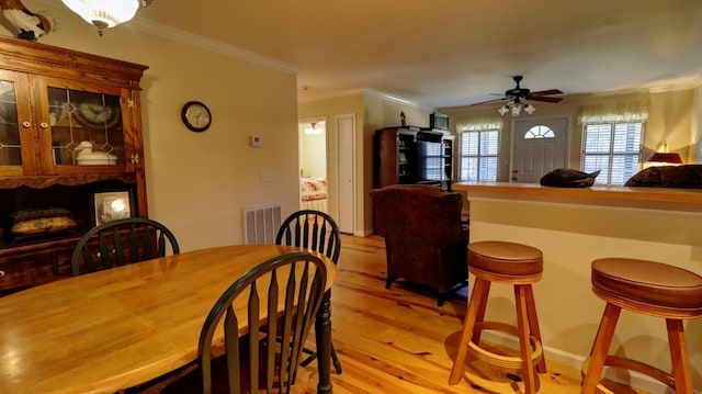 dining room featuring ceiling fan, light wood-type flooring, and crown molding