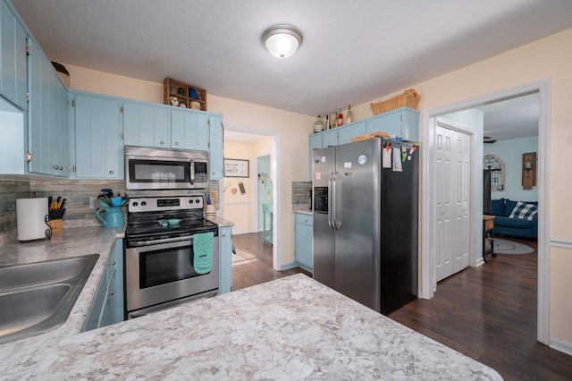 kitchen featuring appliances with stainless steel finishes, backsplash, blue cabinetry, and sink