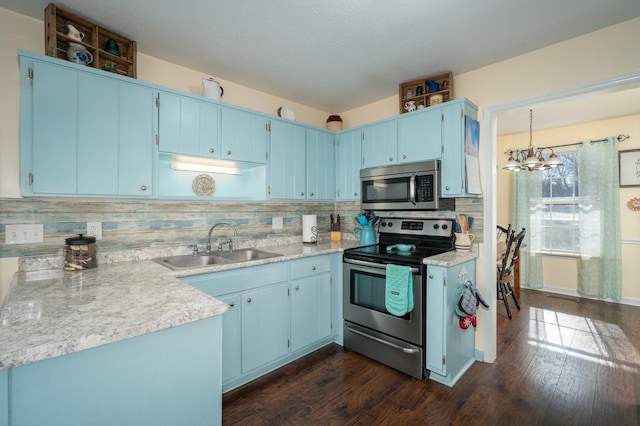 kitchen featuring appliances with stainless steel finishes, pendant lighting, blue cabinetry, and sink