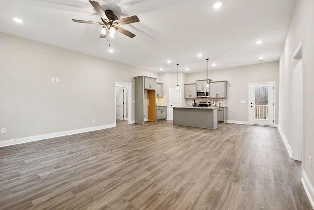 unfurnished living room featuring ceiling fan and hardwood / wood-style flooring