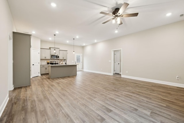 unfurnished living room featuring ceiling fan, light wood-type flooring, and sink