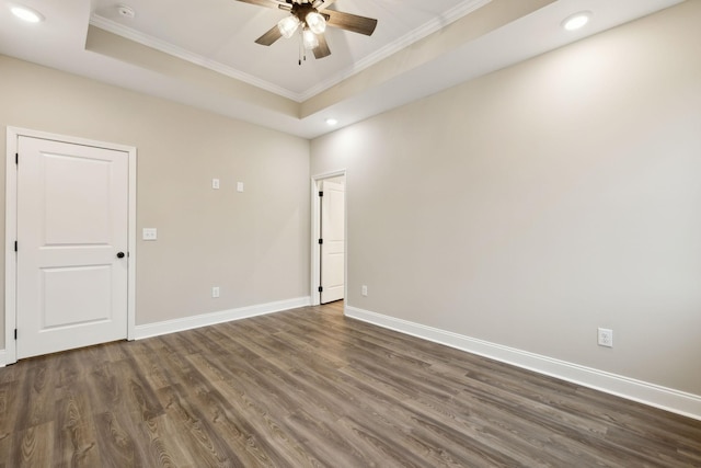 spare room with dark hardwood / wood-style flooring, a tray ceiling, ceiling fan, and ornamental molding