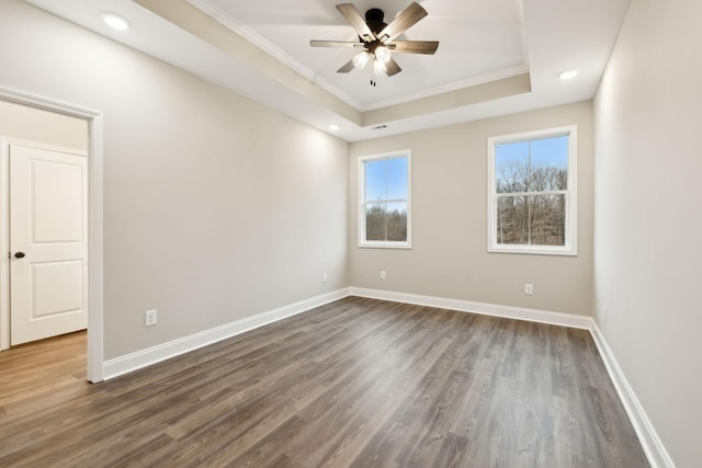 spare room featuring a tray ceiling, dark hardwood / wood-style floors, and ornamental molding