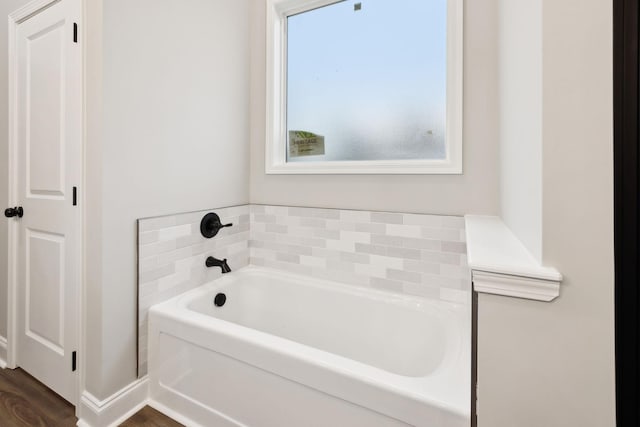 bathroom with hardwood / wood-style flooring, a healthy amount of sunlight, and a tub