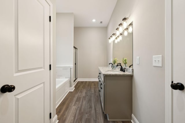 bathroom with hardwood / wood-style flooring, vanity, and plus walk in shower