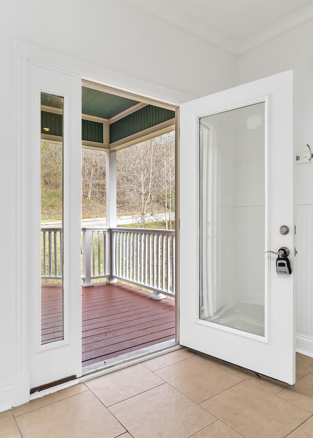 doorway to outside featuring light tile patterned floors and crown molding