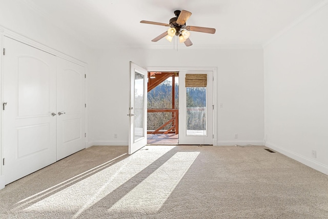 unfurnished bedroom with french doors, light colored carpet, ceiling fan, crown molding, and a closet