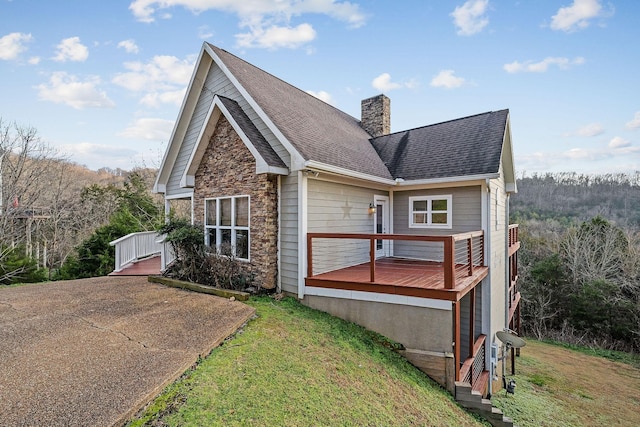 view of side of home featuring a yard and a wooden deck