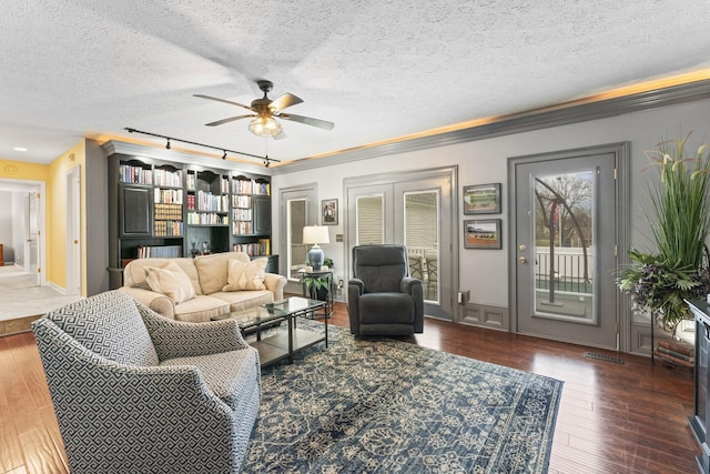 living room with dark hardwood / wood-style flooring, ceiling fan, crown molding, and a textured ceiling