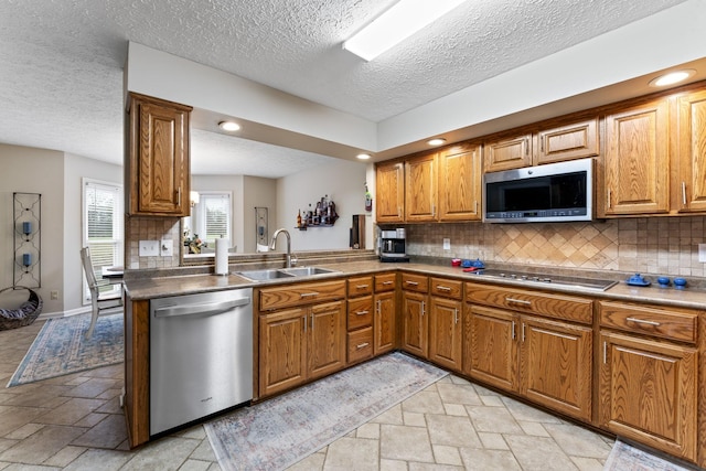 kitchen featuring tasteful backsplash, appliances with stainless steel finishes, kitchen peninsula, and sink