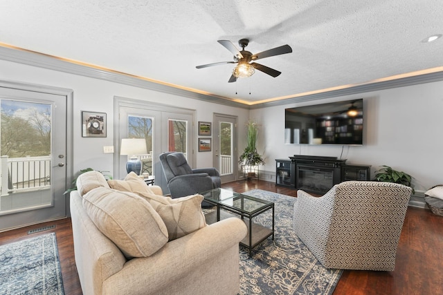 living room with ornamental molding, dark wood-type flooring, ceiling fan, and a textured ceiling