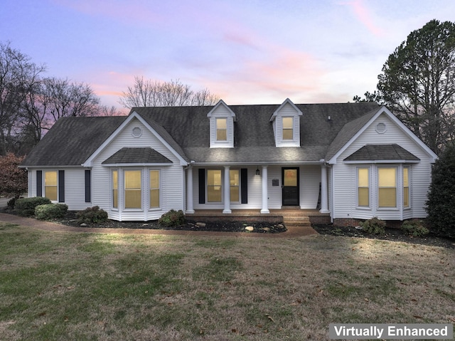 cape cod-style house with a yard and covered porch