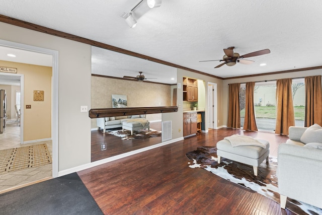 living room with hardwood / wood-style floors, crown molding, a textured ceiling, and ceiling fan