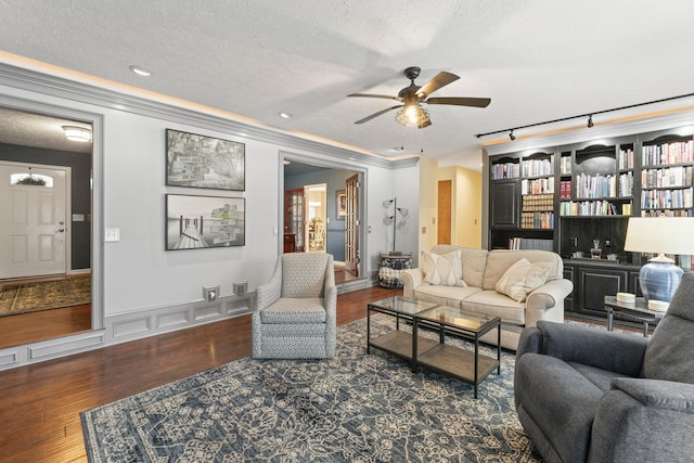 living room with built in features, ceiling fan, ornamental molding, a textured ceiling, and dark hardwood / wood-style flooring