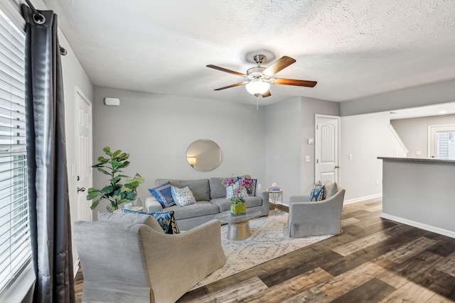 living room featuring a textured ceiling, ceiling fan, and dark wood-type flooring