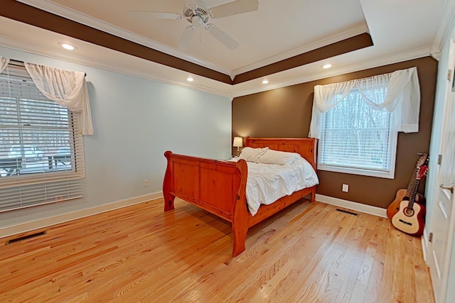 bedroom with ceiling fan, light hardwood / wood-style floors, crown molding, and a tray ceiling