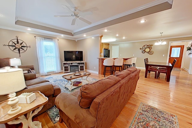 living room featuring light hardwood / wood-style floors, a raised ceiling, and crown molding