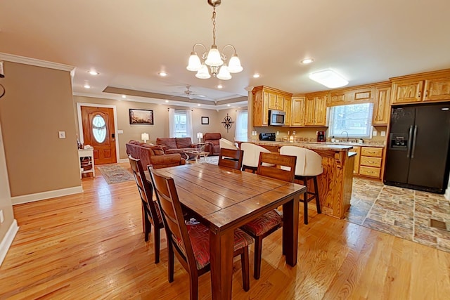 dining room with ceiling fan with notable chandelier, light hardwood / wood-style flooring, ornamental molding, and sink