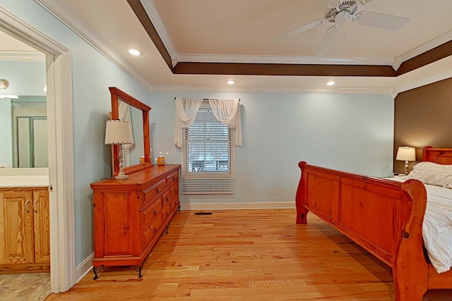 bedroom featuring ensuite bath, ceiling fan, ornamental molding, a tray ceiling, and light hardwood / wood-style floors