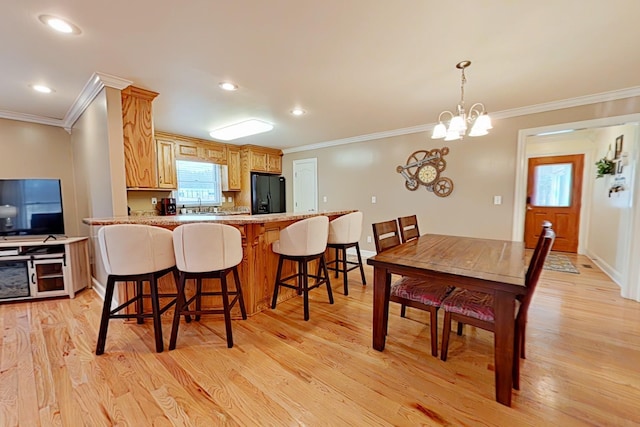 kitchen with black fridge, a notable chandelier, kitchen peninsula, light hardwood / wood-style floors, and ornamental molding