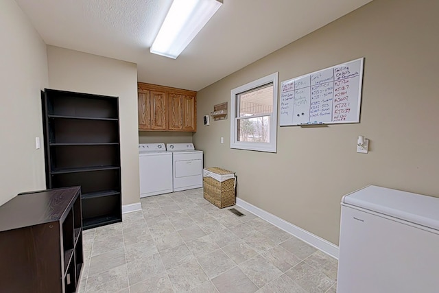 washroom with cabinets, a textured ceiling, and independent washer and dryer