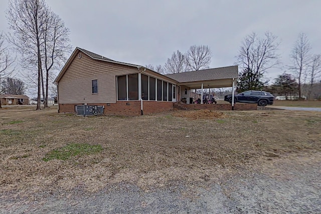 view of home's exterior featuring a carport, central AC unit, and a sunroom