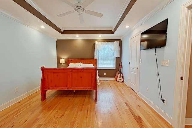 bedroom with a raised ceiling, ceiling fan, crown molding, and light hardwood / wood-style floors