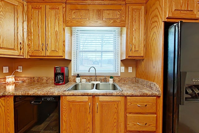 kitchen with black appliances, light stone counters, and sink