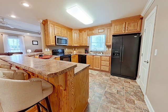 kitchen with kitchen peninsula, a kitchen breakfast bar, ceiling fan, sink, and black appliances