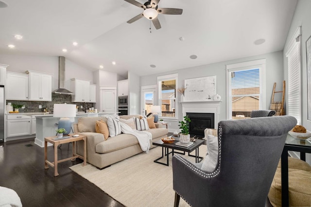 living room featuring ceiling fan, plenty of natural light, vaulted ceiling, and light wood-type flooring