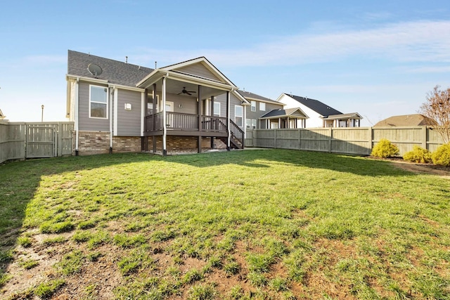 rear view of house featuring ceiling fan, a yard, and a wooden deck