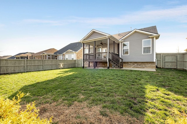 rear view of property featuring a yard and ceiling fan