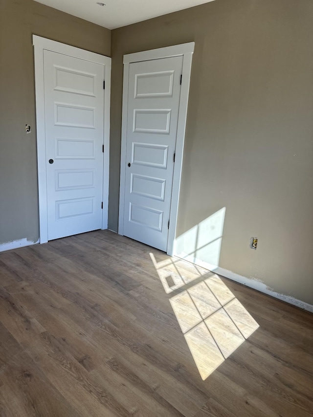 spare room with baseboards and wood finished floors