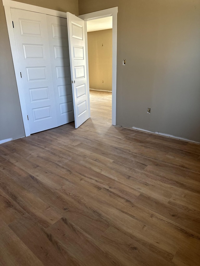 unfurnished bedroom with wood finished floors and a closet